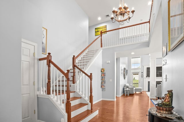 stairway featuring visible vents, baseboards, wood finished floors, a high ceiling, and recessed lighting