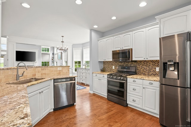 kitchen with appliances with stainless steel finishes, light wood-type flooring, backsplash, and white cabinetry