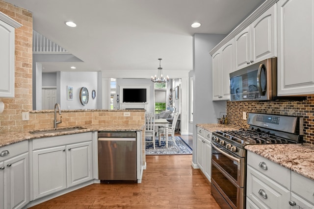 kitchen featuring light hardwood / wood-style flooring, white cabinets, backsplash, appliances with stainless steel finishes, and sink