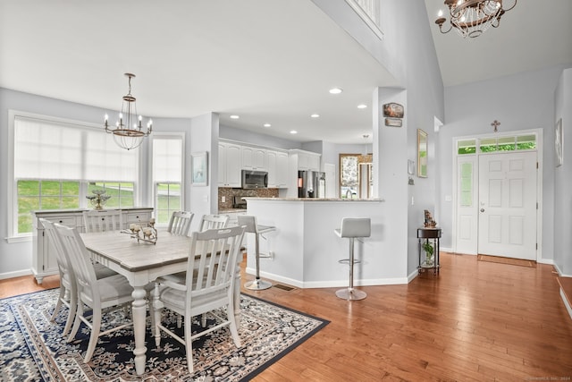 dining area with light hardwood / wood-style flooring, an inviting chandelier, and vaulted ceiling