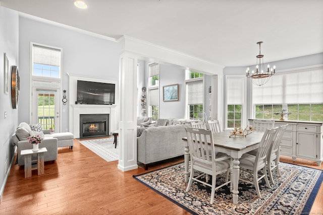 dining area featuring a chandelier, a lit fireplace, light wood-type flooring, and recessed lighting