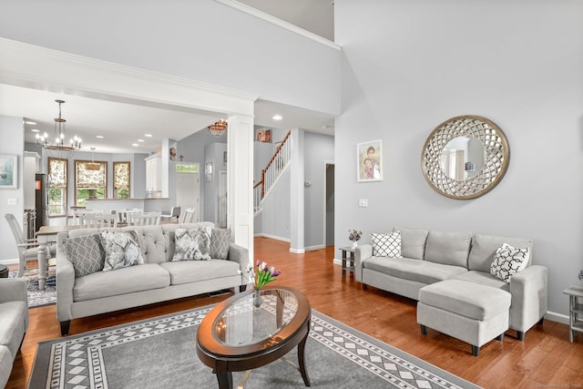 living area with stairway, wood finished floors, and a notable chandelier