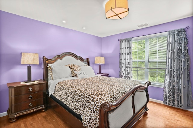 bedroom with wood finished floors, visible vents, and baseboards