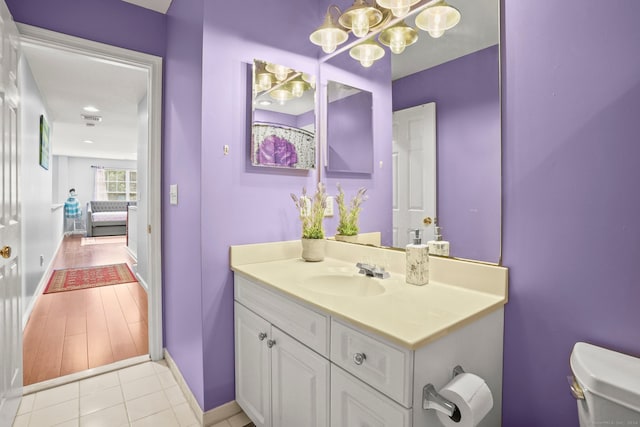 bathroom featuring an inviting chandelier, vanity, hardwood / wood-style flooring, and toilet