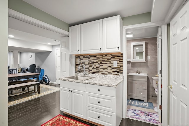 kitchen featuring sink, white cabinetry, wood-type flooring, and backsplash