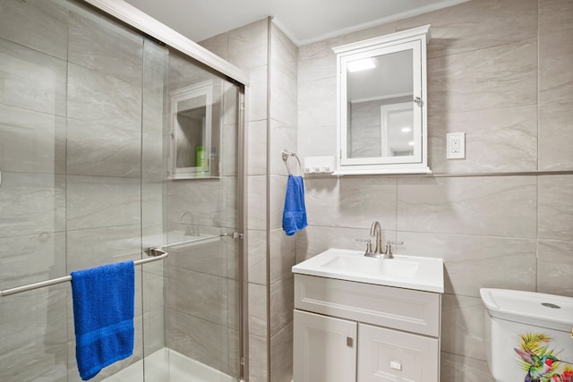 bathroom with vanity, a shower with shower door, toilet, and tile walls