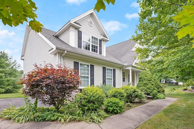 view of front of home with a shingled roof and a front lawn