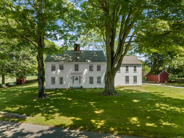 colonial-style house featuring an outdoor structure and a front yard