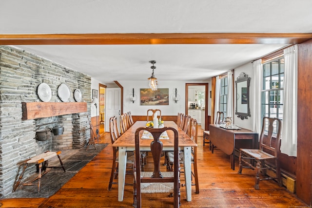 dining area with hardwood / wood-style floors and a stone fireplace