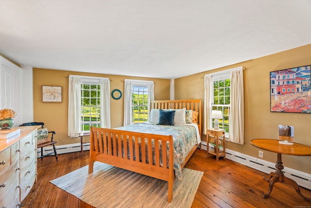 bedroom with multiple windows, dark hardwood / wood-style flooring, and baseboard heating