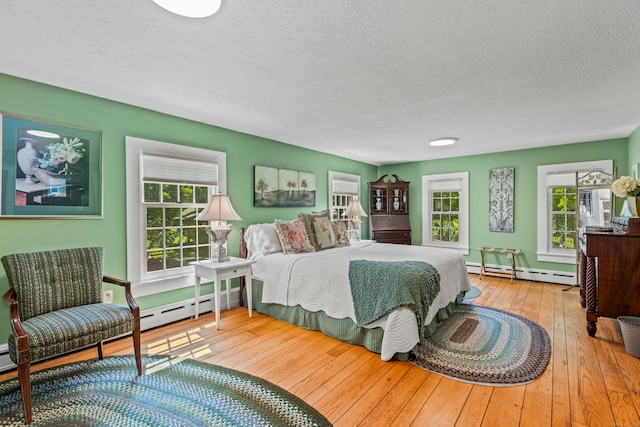 bedroom with a textured ceiling, light hardwood / wood-style floors, and a baseboard radiator