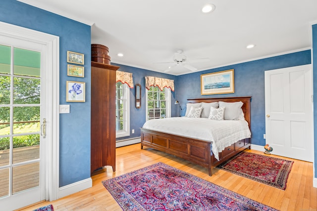 bedroom featuring light wood-type flooring, a baseboard heating unit, ceiling fan, and multiple windows