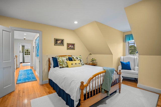 bedroom featuring light hardwood / wood-style flooring, lofted ceiling, and multiple windows