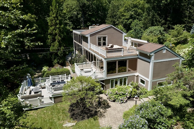 rear view of property with a balcony and a wooded view