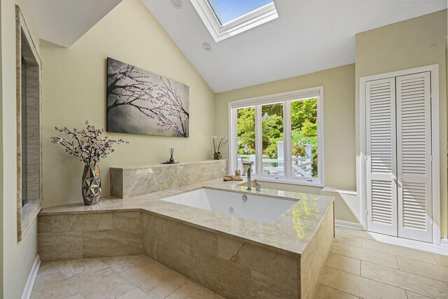 bathroom featuring lofted ceiling with skylight, sink, and tile patterned flooring