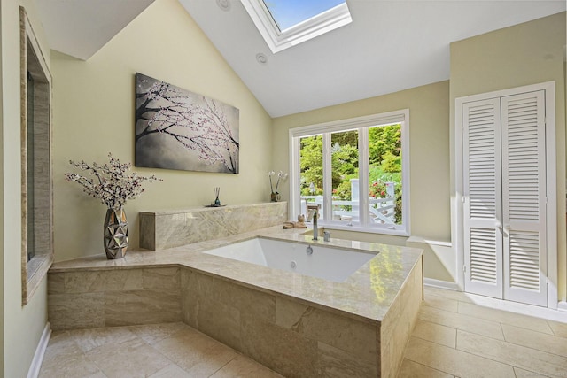 bathroom with high vaulted ceiling, a skylight, a sink, baseboards, and a bath