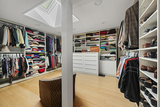 walk in closet with a skylight and wood finished floors