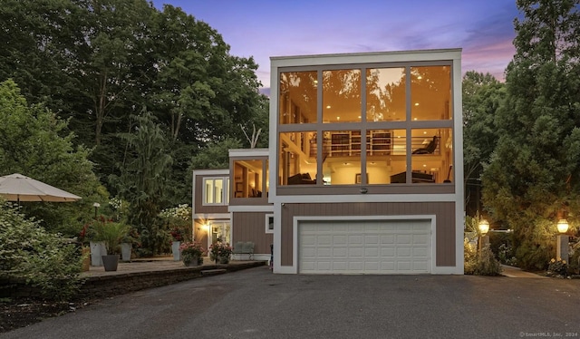 contemporary house featuring a balcony, a garage, and aphalt driveway