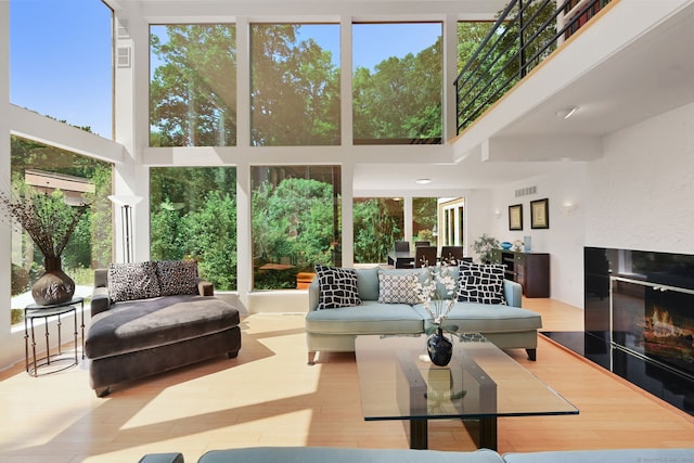 living room with a high ceiling, light wood-type flooring, and plenty of natural light