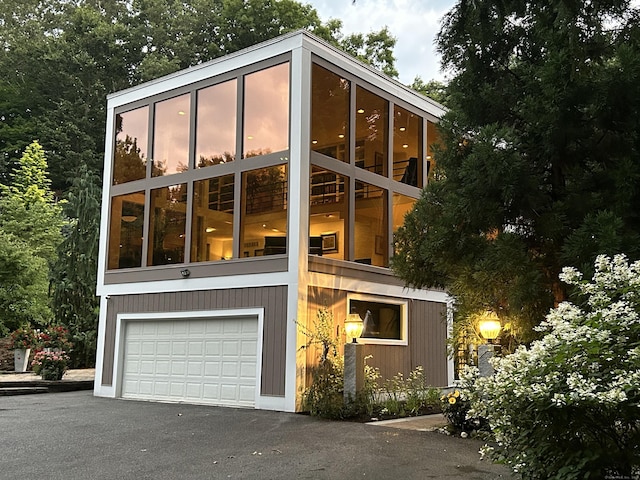 view of side of home with a garage, driveway, and a sunroom