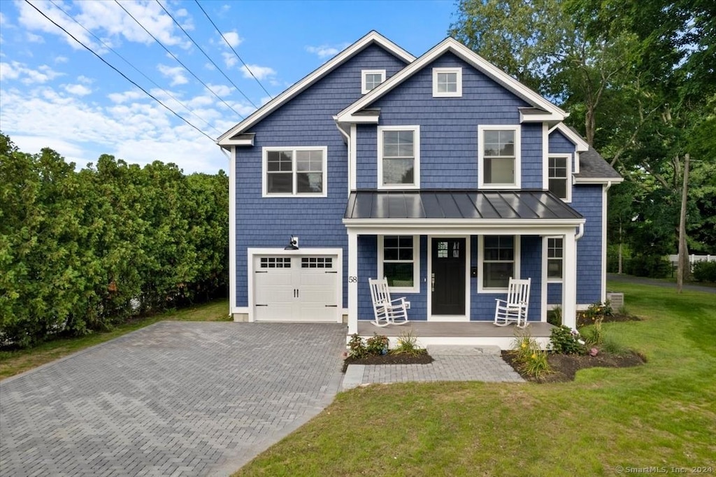 view of front of home featuring covered porch, a front lawn, a standing seam roof, and decorative driveway