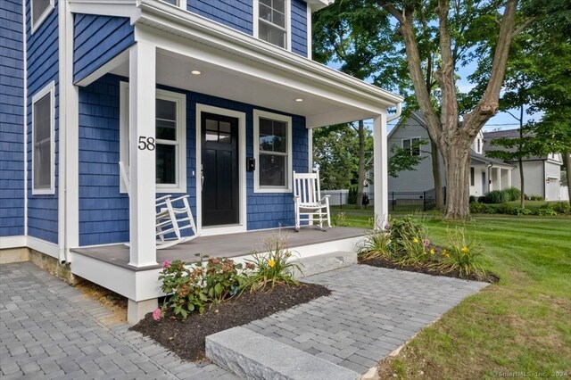 doorway to property featuring a porch and a yard