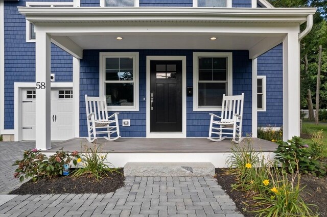 view of exterior entry featuring a porch and a garage