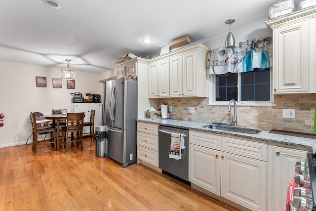 kitchen featuring pendant lighting, stainless steel appliances, sink, and light wood-type flooring