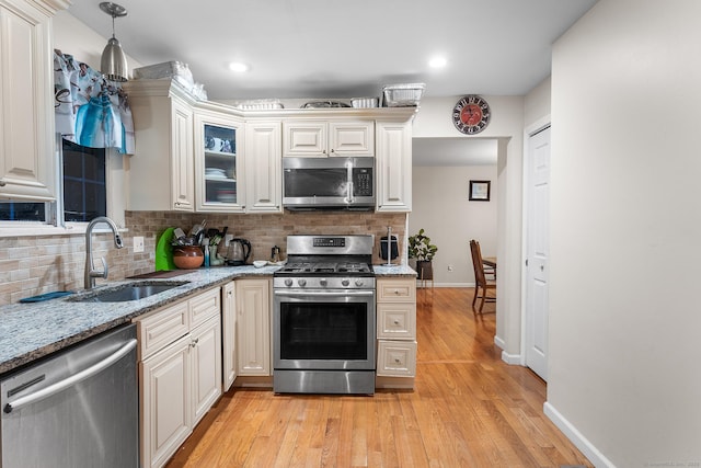 kitchen with sink, decorative backsplash, stainless steel appliances, and light wood-type flooring