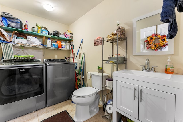 clothes washing area with sink, light tile patterned floors, and washer and clothes dryer