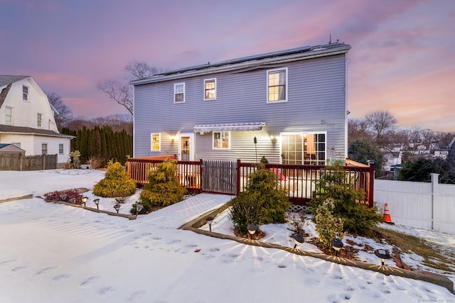 snow covered house with a wooden deck