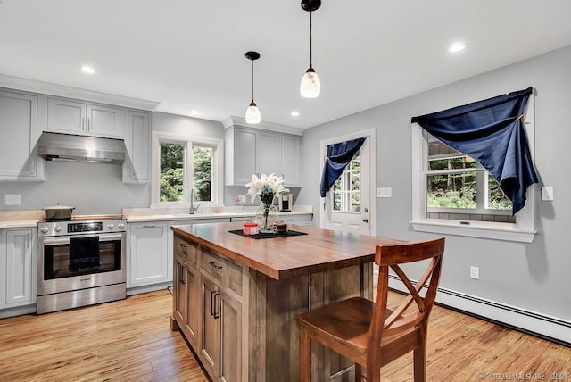 kitchen featuring wood counters, baseboard heating, a kitchen island, pendant lighting, and stainless steel stove