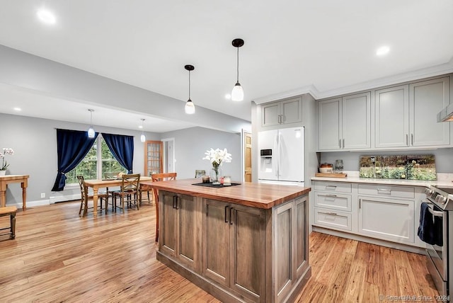 kitchen with stainless steel electric stove, white refrigerator with ice dispenser, hanging light fixtures, and wooden counters