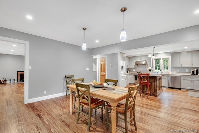 dining space featuring a fireplace, light hardwood / wood-style floors, and sink