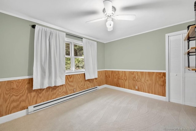 carpeted spare room with ceiling fan, ornamental molding, and a baseboard radiator