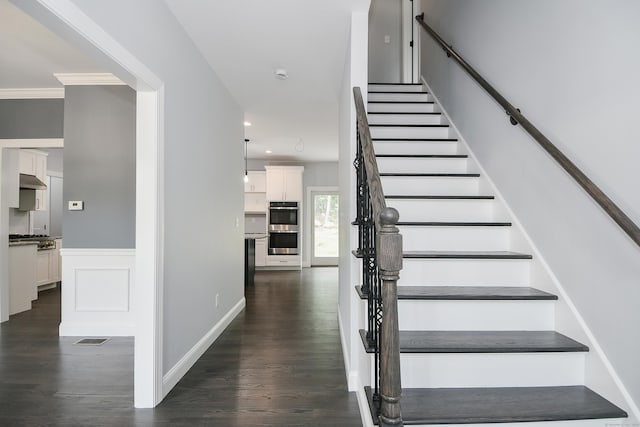 stairway with wood-type flooring and ornamental molding