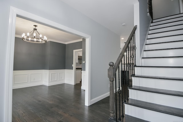 staircase featuring a chandelier, hardwood / wood-style floors, and ornamental molding