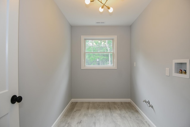 empty room with light hardwood / wood-style floors and an inviting chandelier