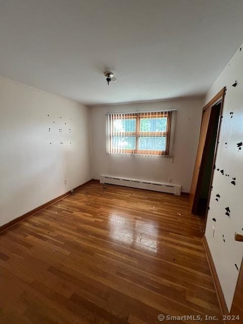 unfurnished room with baseboard heating and hardwood / wood-style floors