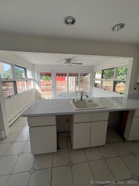 kitchen with white cabinetry, kitchen peninsula, sink, and light tile patterned floors