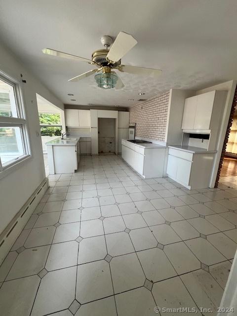 kitchen with a kitchen island, sink, white cabinets, and ceiling fan