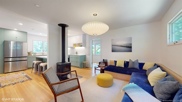 living room featuring light wood-type flooring, plenty of natural light, and a wood stove