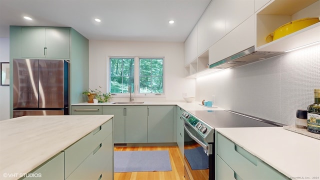 kitchen featuring stainless steel appliances, green cabinetry, light hardwood / wood-style floors, and sink