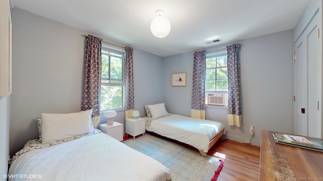 bedroom featuring cooling unit, light hardwood / wood-style flooring, and multiple windows