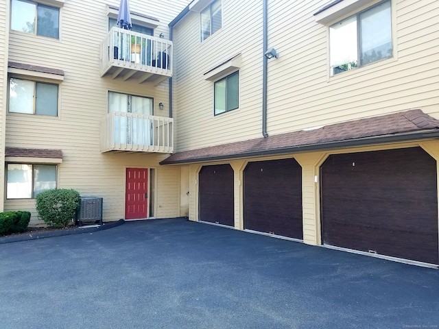 exterior space with cooling unit, driveway, and an attached garage