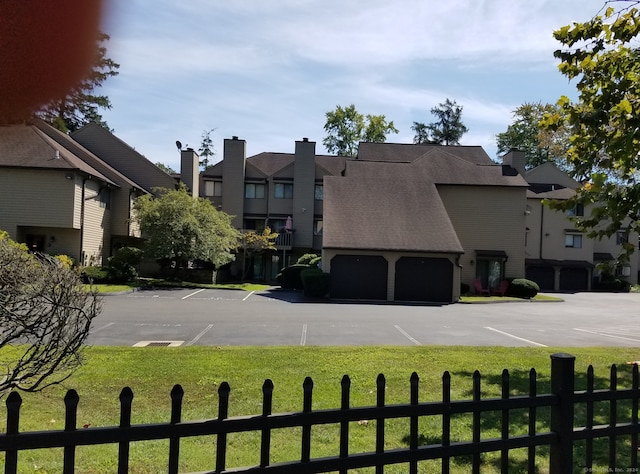 view of building exterior with a fenced front yard, a residential view, and uncovered parking