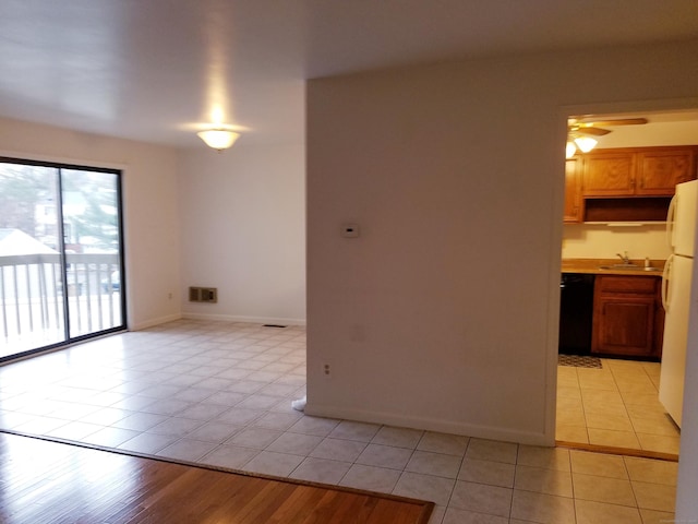 empty room featuring a ceiling fan, a sink, baseboards, and light tile patterned floors