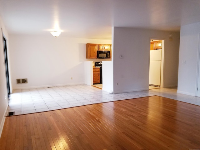 unfurnished living room featuring light wood finished floors, visible vents, and baseboards