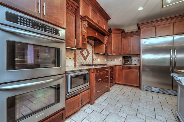 kitchen featuring built in appliances, light stone countertops, and tasteful backsplash