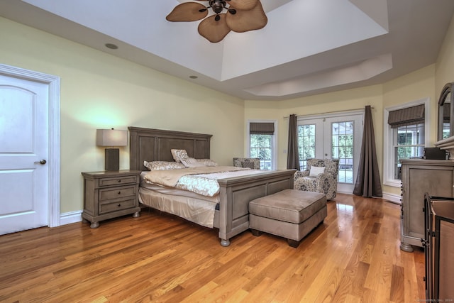 bedroom featuring ceiling fan, hardwood / wood-style flooring, multiple windows, and a tray ceiling